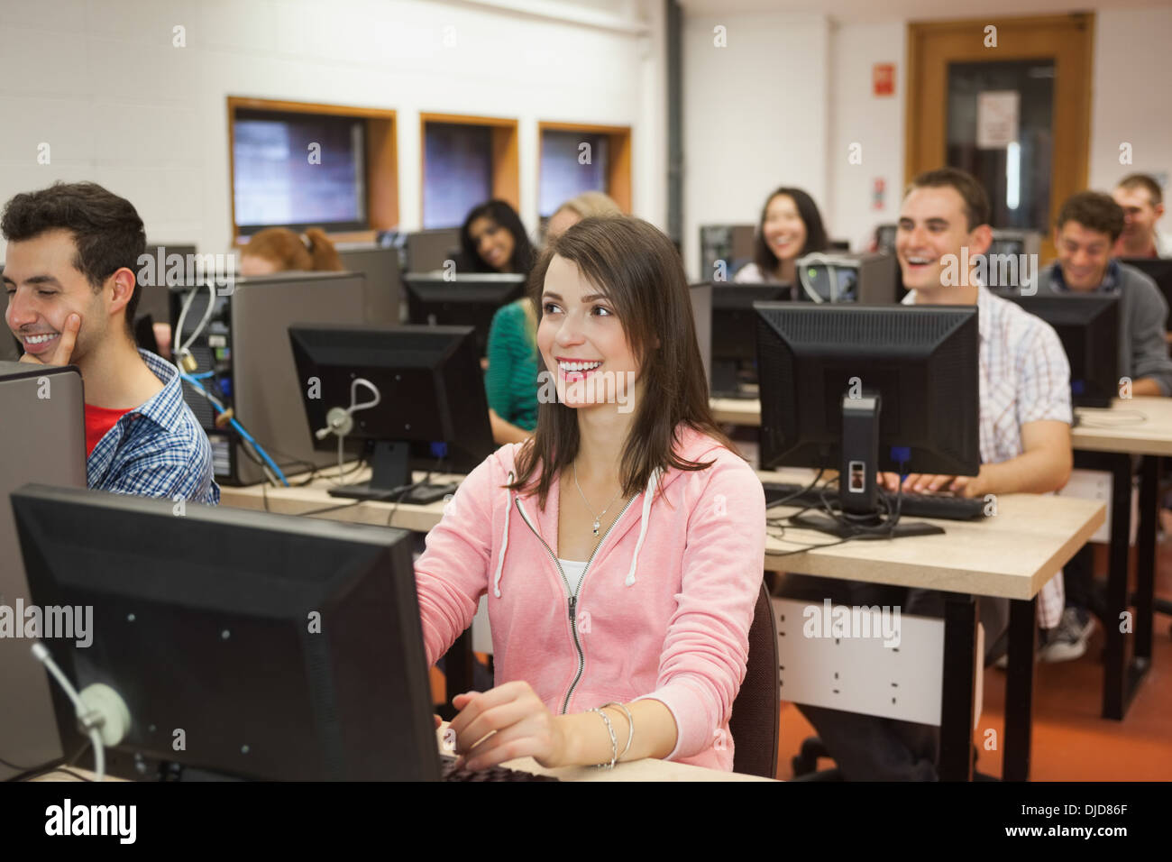 Smiling students listening dans leur classe d'ordinateur Banque D'Images