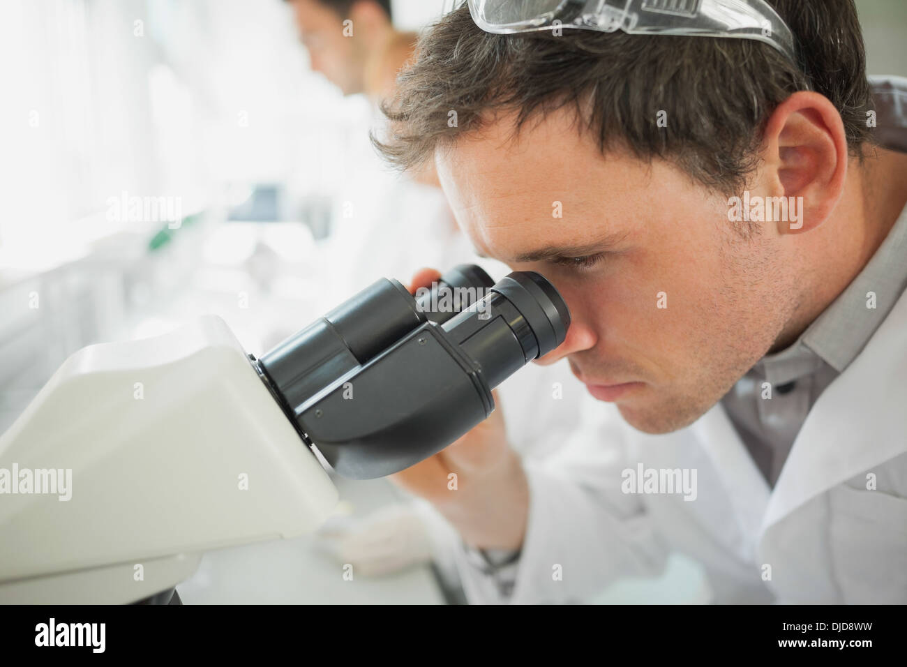 Jeune homme à la recherche scientifique à l'aide d'un microscope Banque D'Images