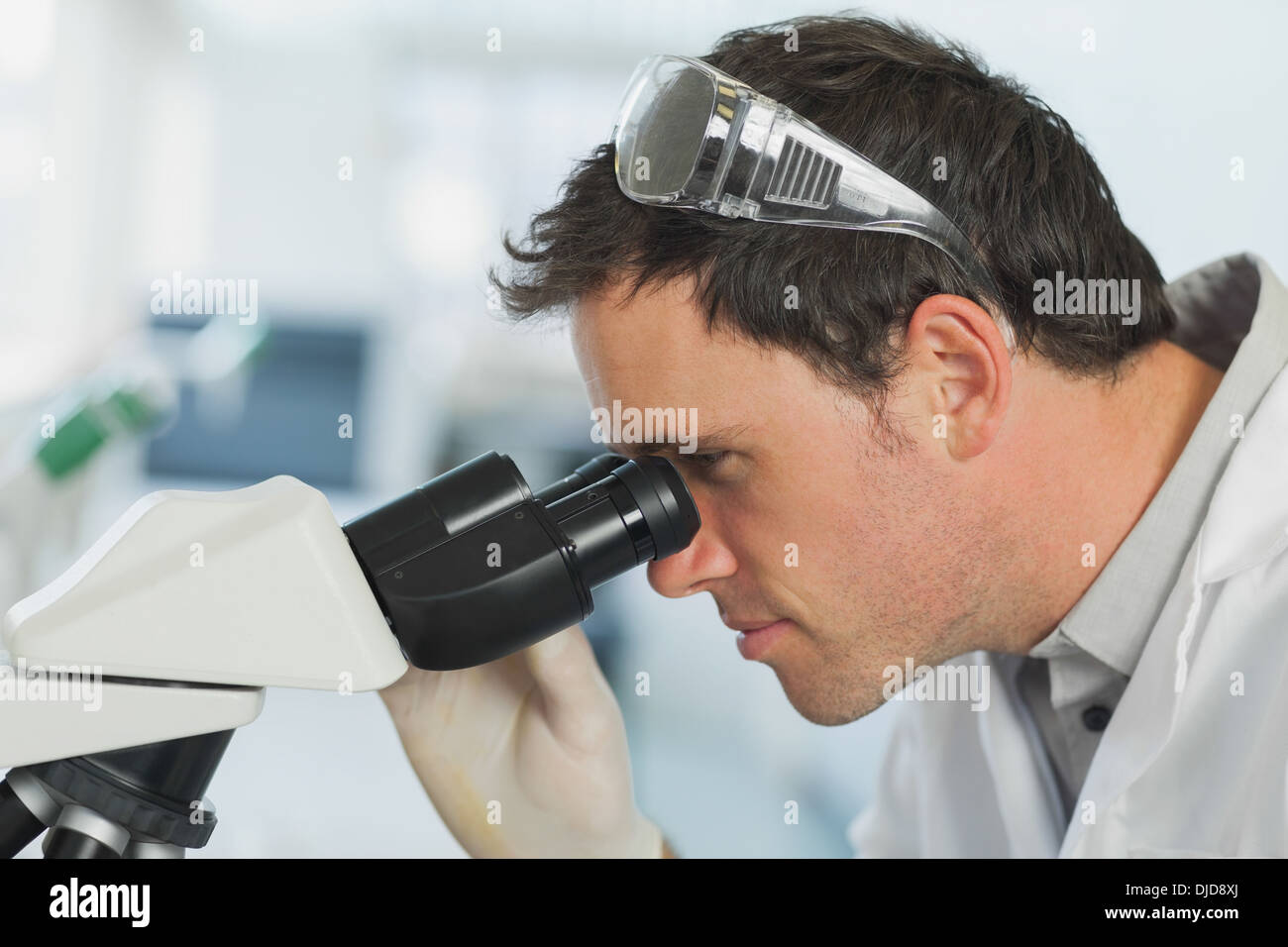 Beau jeune scientifique à la recherche à l'aide d'un microscope Banque D'Images