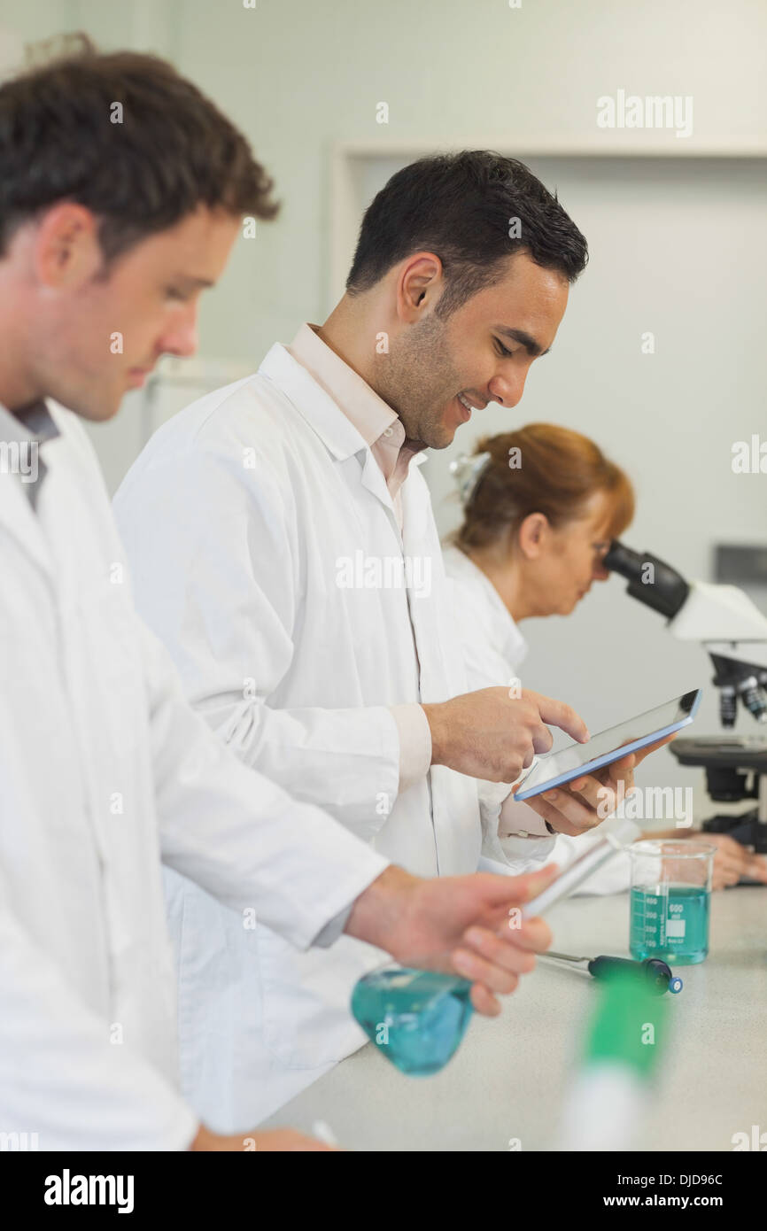 Amusé du jeune scientifique travaillant avec sa tablette Banque D'Images