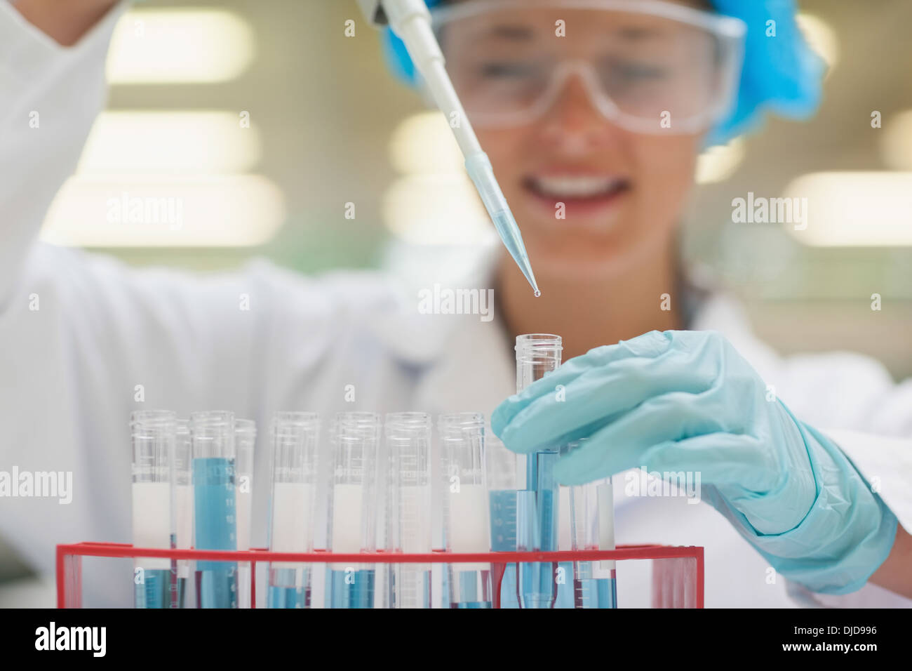 Smiling student using pipette holding test tube Banque D'Images