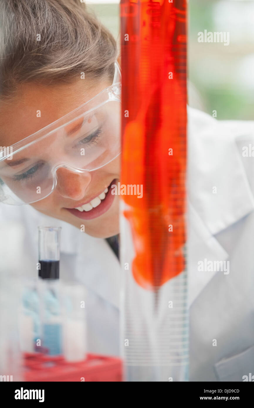 Smiling student regarder liquide rouge in beaker Banque D'Images