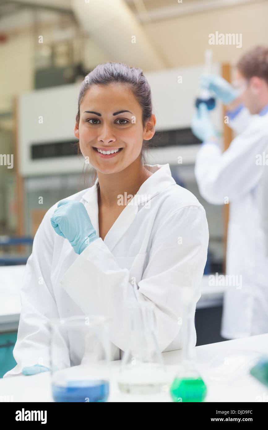 Smiling attractive student in lab coat looking at camera Banque D'Images