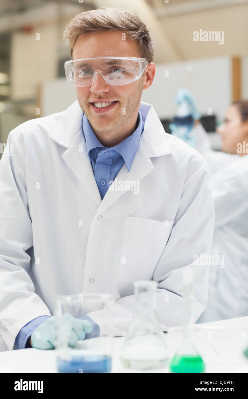 Smiling handsome student in lab coat looking at camera Banque D'Images