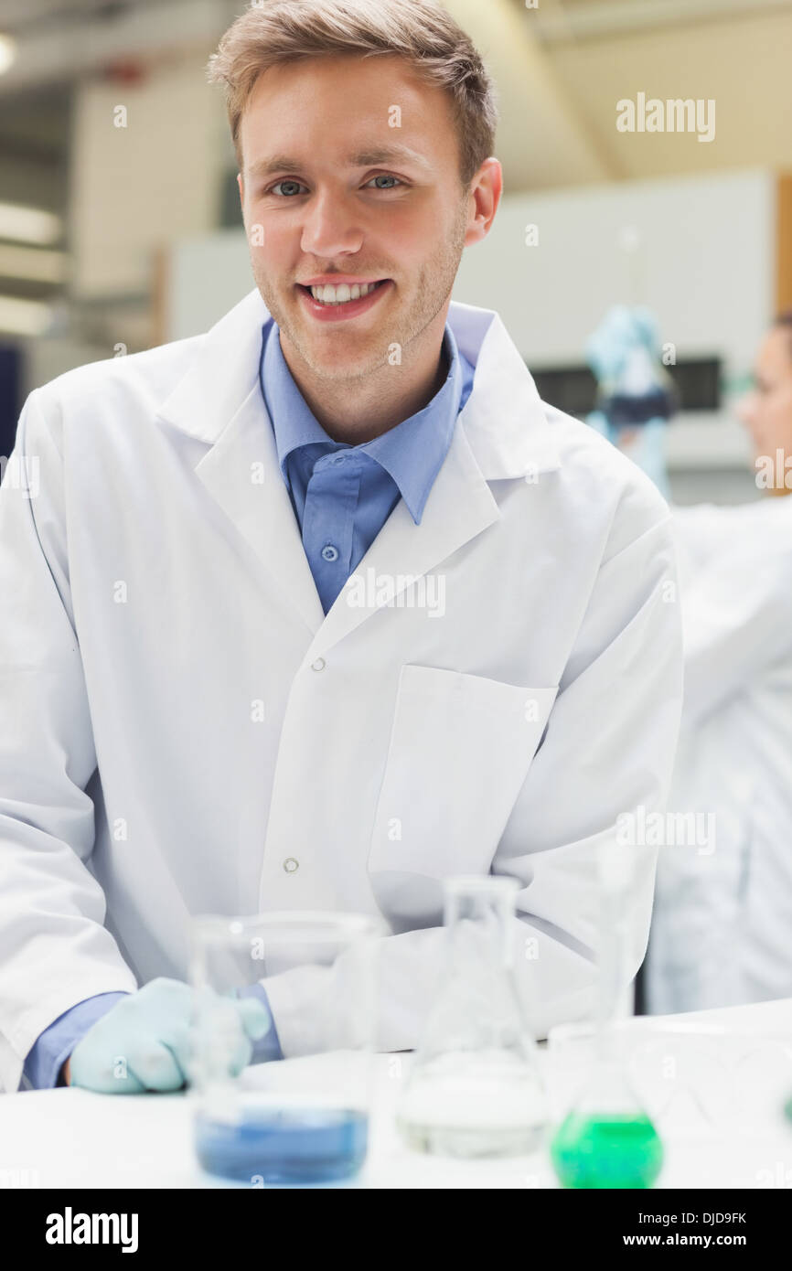 Cheerful handsome student in lab coat looking at camera Banque D'Images