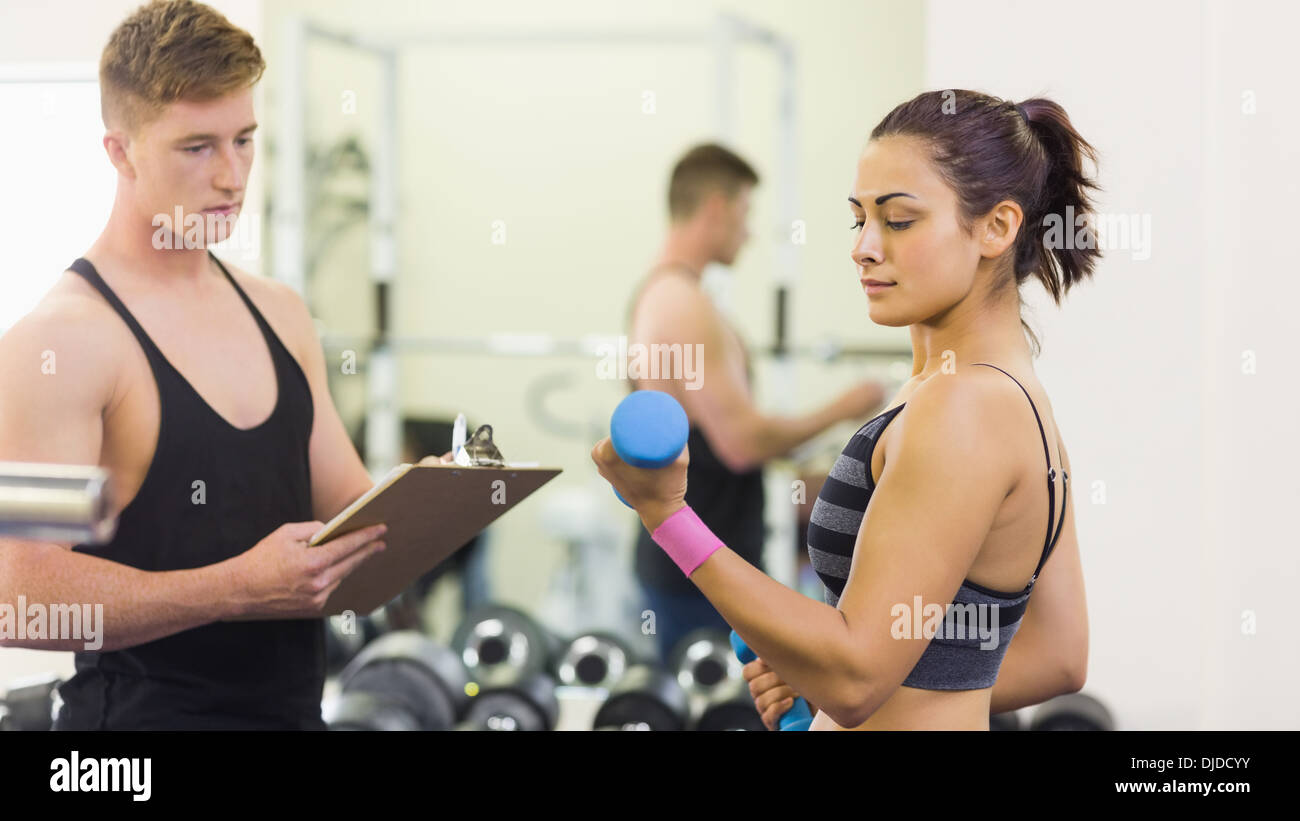 La prise de notes au formateur de femme avec haltères Banque D'Images