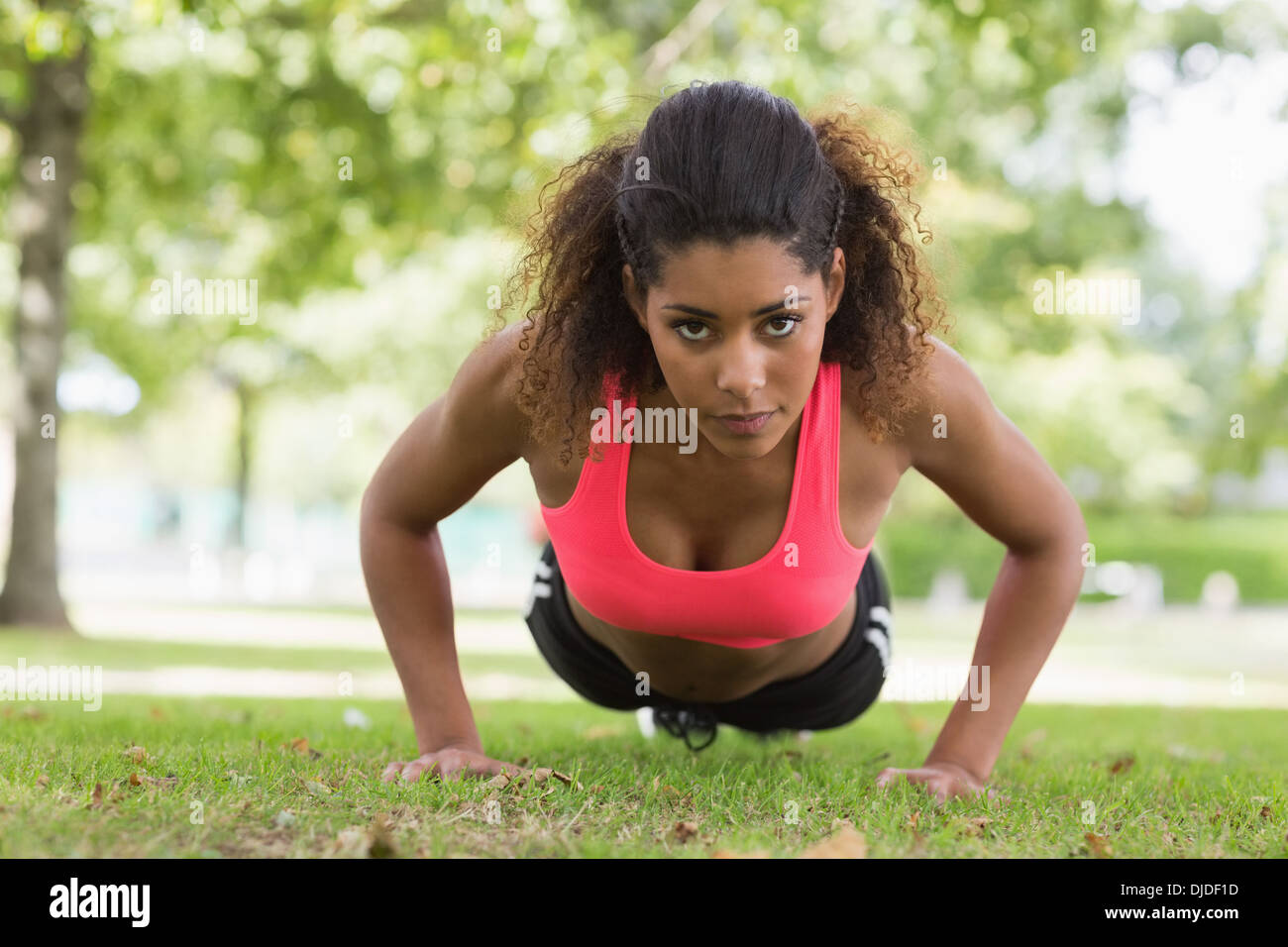 Belle jeune femme sérieuse faisant pousser ups in park Banque D'Images