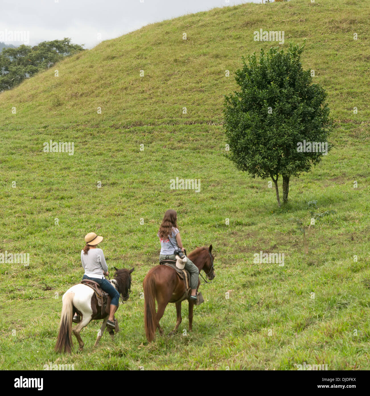 Une fille et sa mère l'équitation à travers les collines ; Hotel El Cisne, Honduras Banque D'Images