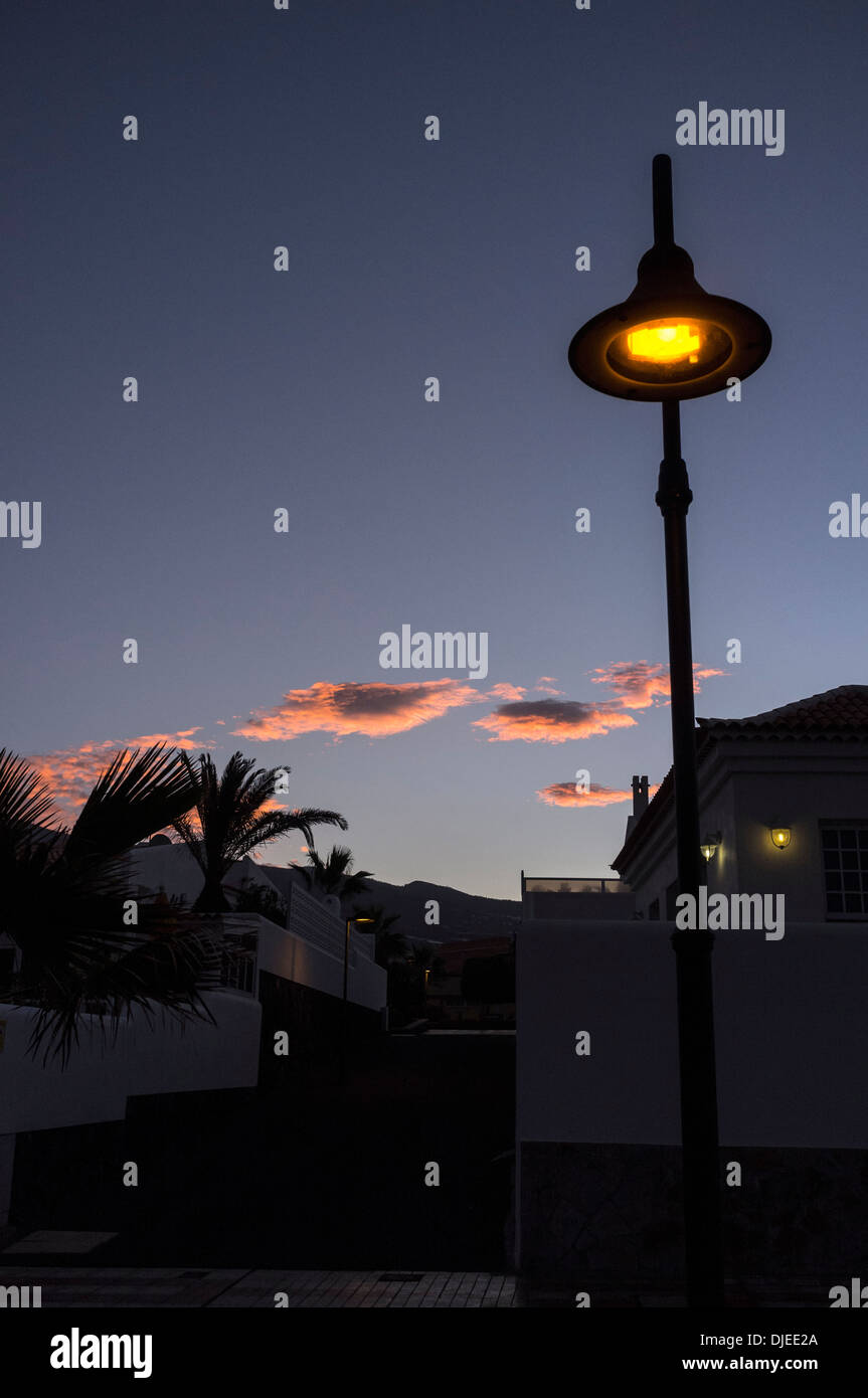 Lampe de rue et des nuages rouges à l'aube avec villa et palmiers derrière, Tenerife, Canaries, Espagne Banque D'Images Lampe de rue et des nuages rouges à l'aube avec villa et palmiers derrière, Tenerife, Canaries, Espagne Banque D'Images