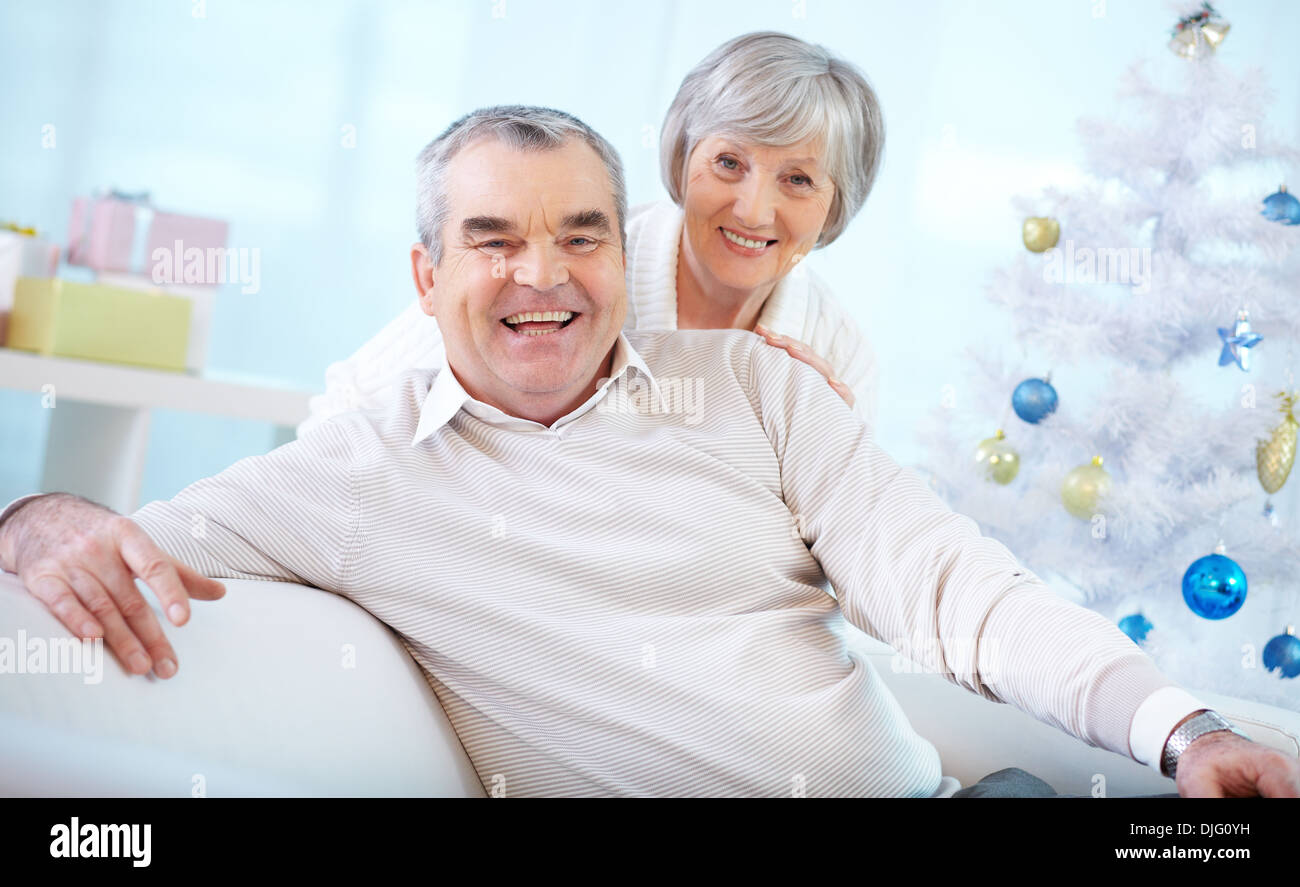 Portrait of a happy senior couple looking at camera sur fond d'arbre de Noël décoré Banque D'Images
