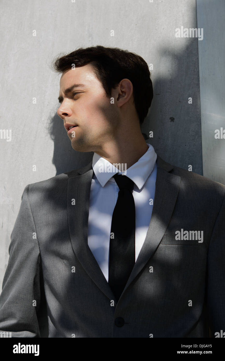 Un bel homme, jeune homme d'affaires à l'écart, appuyé contre un mur de  ciment gris. Il est habillé d'un costume gris, cravate noire Photo Stock -  Alamy