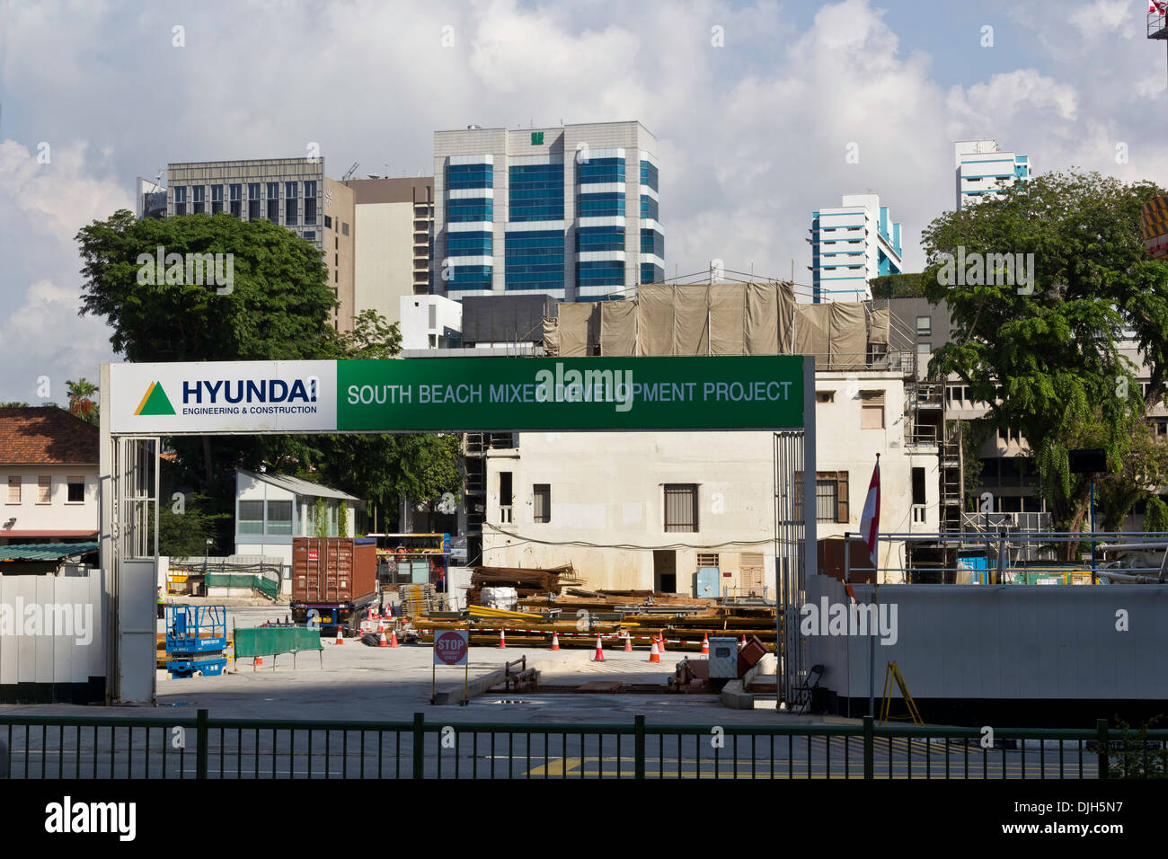 Un chantier de construction à Singapour avec des grues et beaucoup de travail. Le site est entouré de grands bâtiments et d'arbres. Banque D'Images