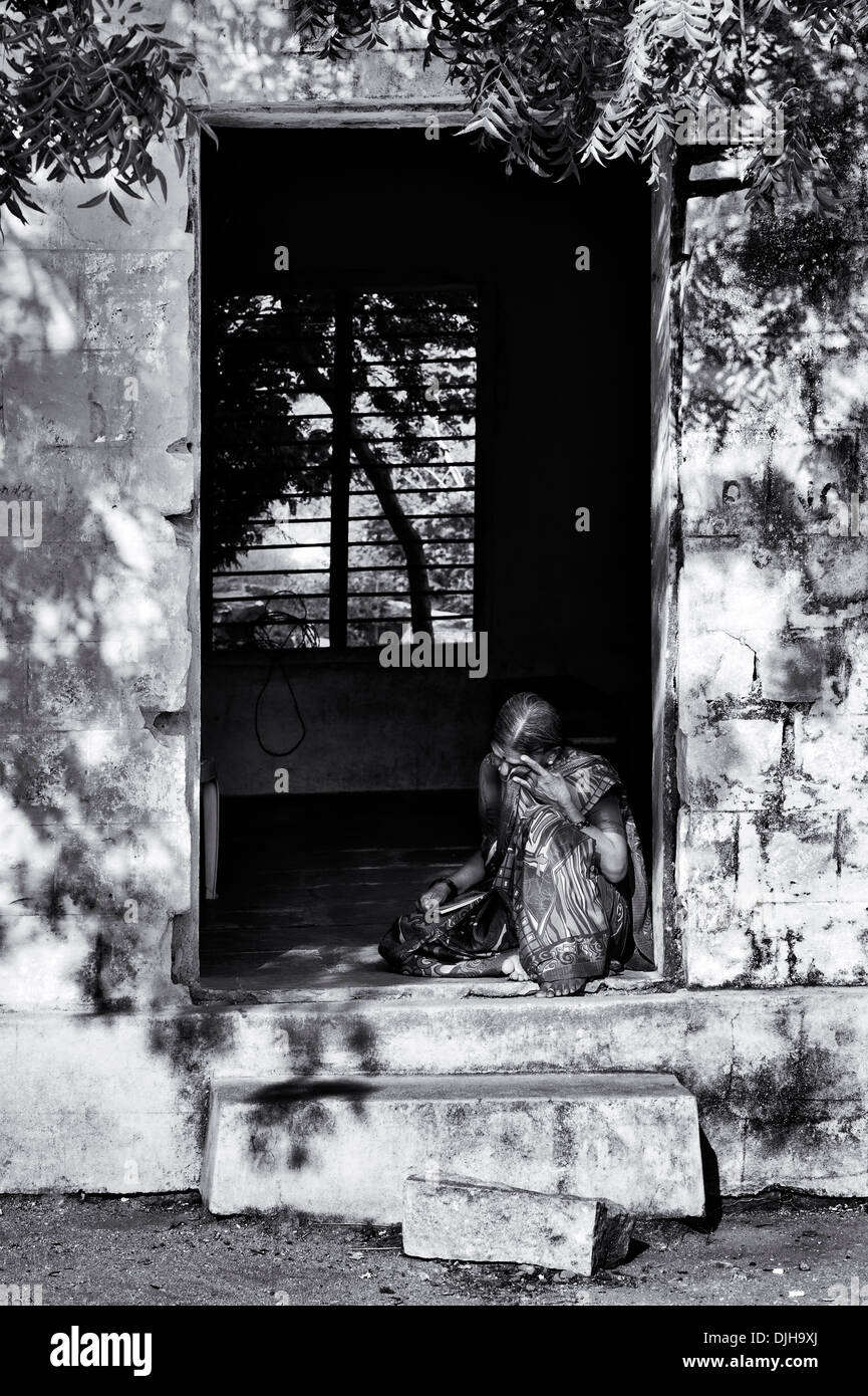 Vieille Femme indienne était assis dans une porte à l'Sri Sathya Sai Baba mobiles de proximité hôpital clinique. L'Andhra Pradesh, Inde. Monochrome Banque D'Images
