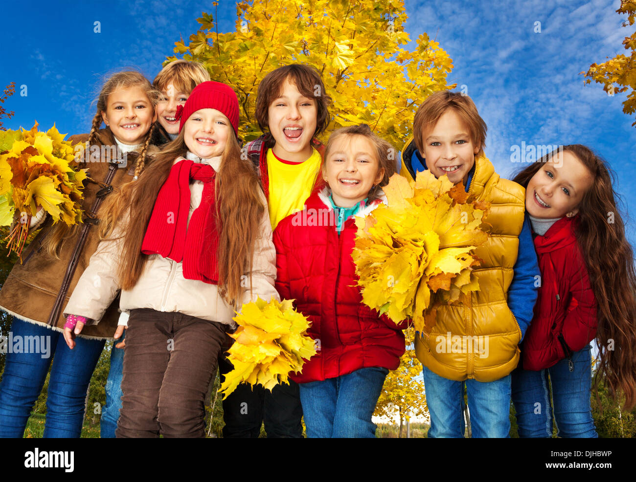 Groupe des sept enfants autour de 10 ans, garçons et filles, debout ensemble dans le parc avec Jaune automne érable on background Banque D'Images