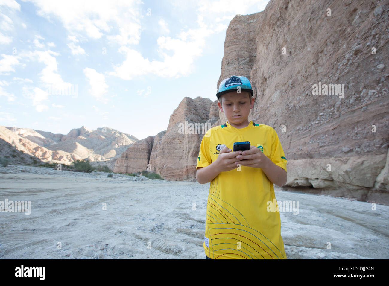 Un garçon vérifie son téléphone à Split Montagne canyon, Anza Borrego Desert State Park, San Diego County, Californie, USA. Banque D'Images