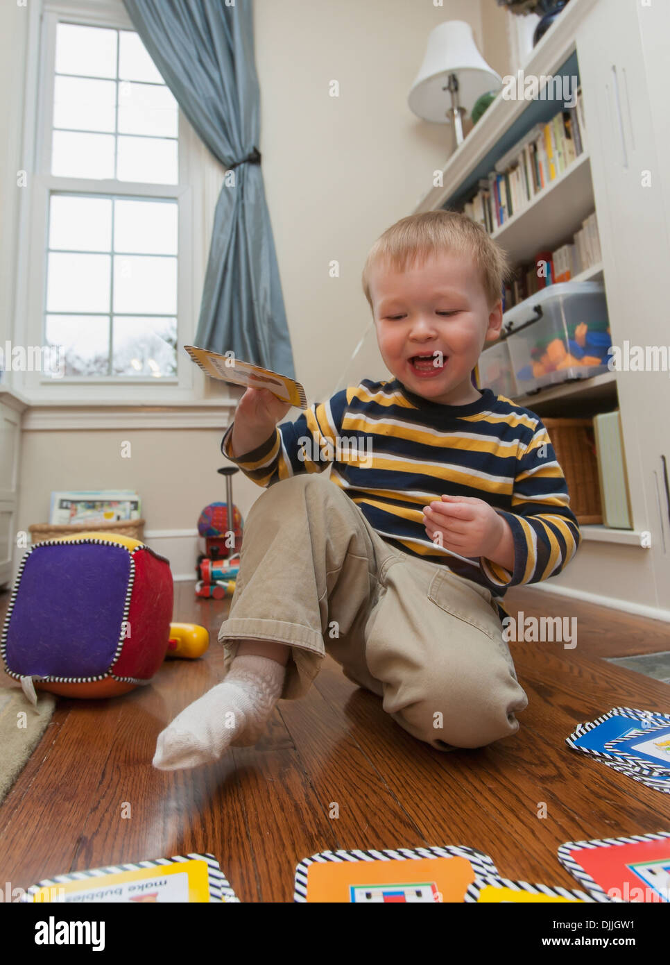 Une prise de vue au grand angle d'un air amusé, heureux, un garçon de deux ans jouant lui-même avec un jeu sur le sol à son domicile Banque D'Images