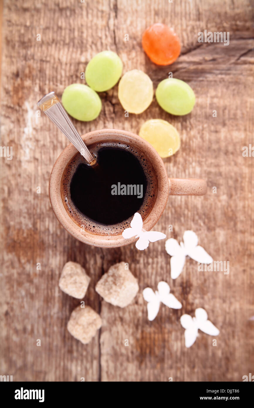 Image tonique, tasse de café noir, sucre brun, cuillère, papillons, papier de fond en bois Banque D'Images