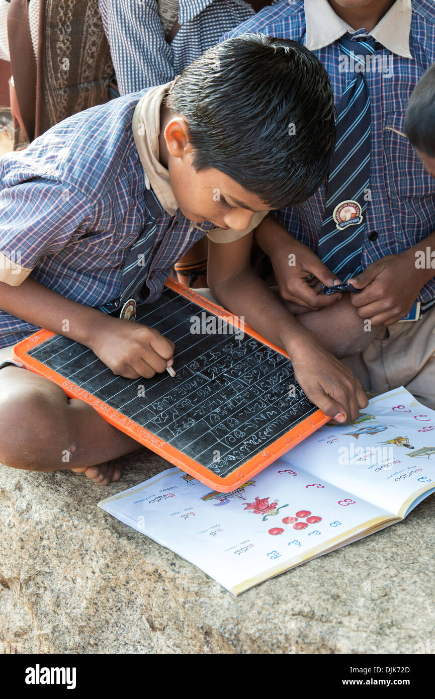 Garçons de l'école village écrit telegu sur une tablette de craie dans une classe de l'extérieur. L'Andhra Pradesh, Inde Banque D'Images