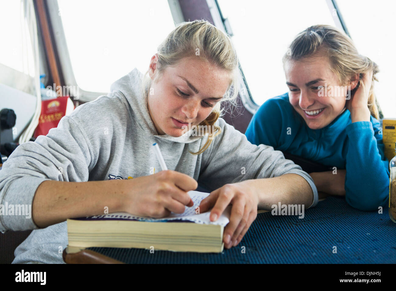 Laukitis Emma écrit sur leur bateau de pêche commercial comme sa soeur Claire regarde sur, faux col Banque D'Images