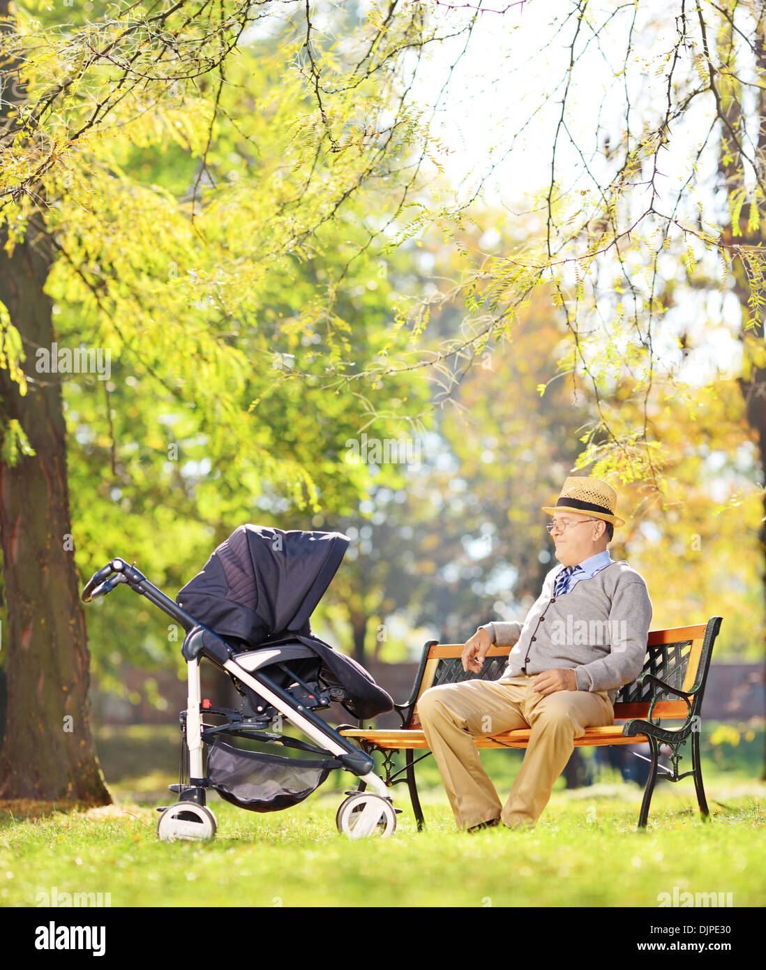 Grand-père assis sur un banc et en regardant son neveu bébé dans une poussette, dans un parc Banque D'Images