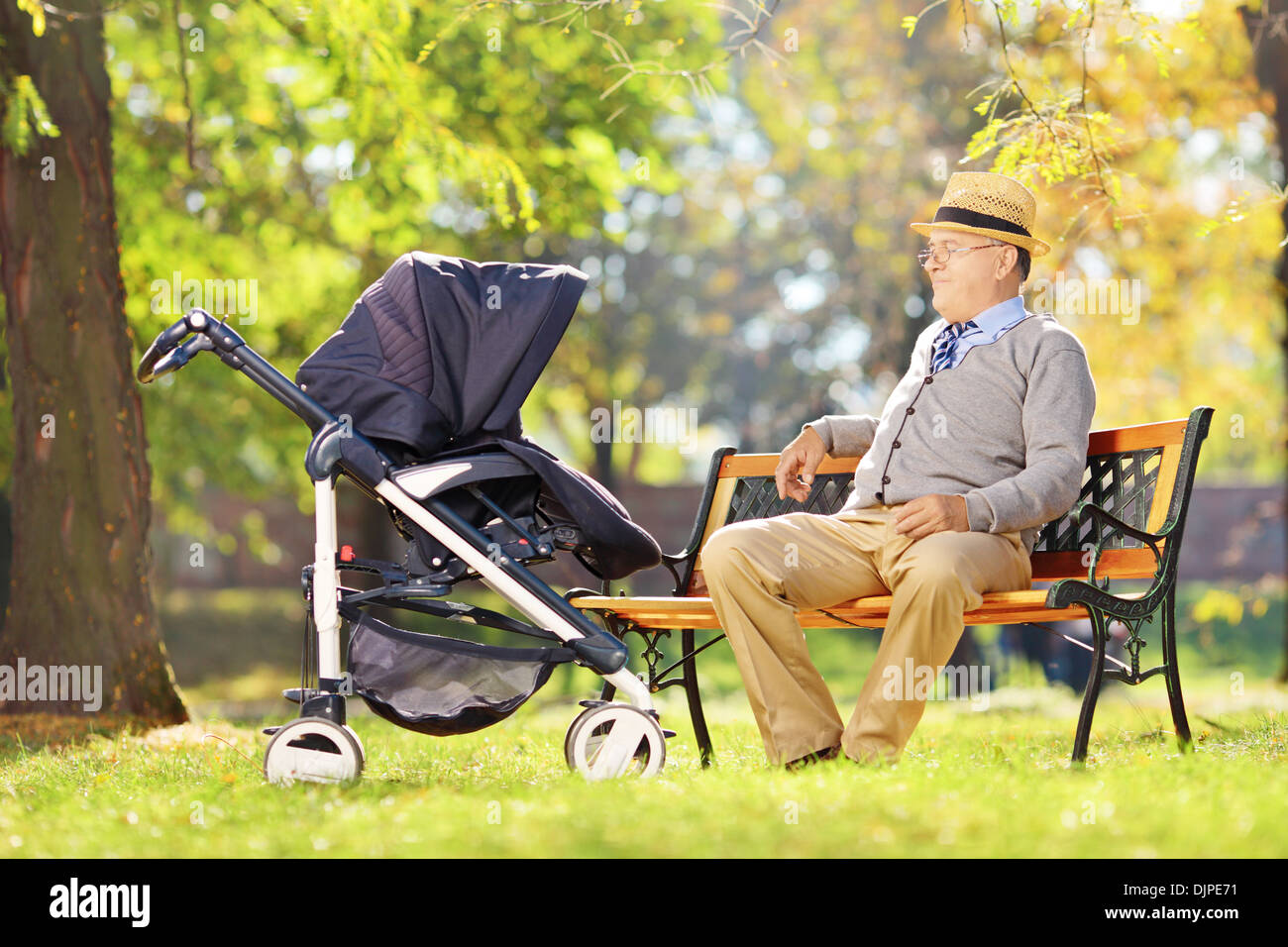 Grand-père assis sur un banc en bois et en regardant son neveu dans une poussette, dans un parc Banque D'Images