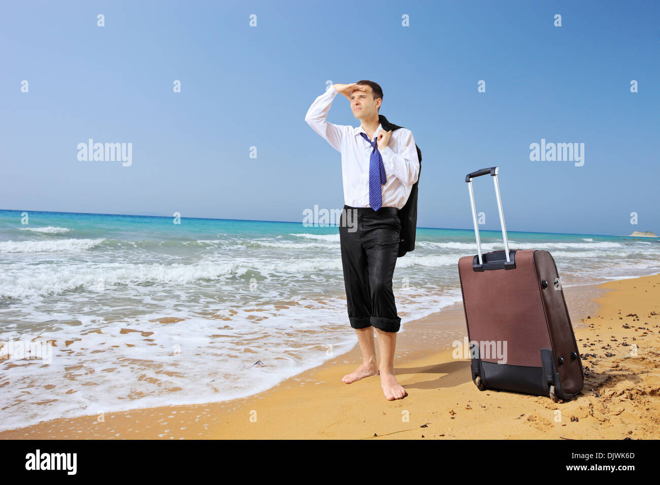 Portrait d'un homme perdu avec ses bagages à la recherche de cours sur une plage Banque D'Images