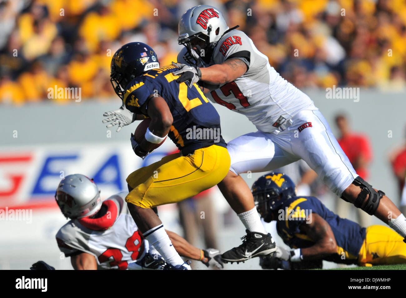 9 octobre 2010 - Morgantown, West Virginia, United States of America - West Virginia Johnson Trey running back (27) est abordé par UNLV defender Daniel Mareko (47) au cours du premier semestre. La Virginie de l'Ouest conduit par un score de 35 - 0 à la mi-temps. (Crédit Image : © Brian Freed/ZUMApress.com) Southcreek/mondial Banque D'Images