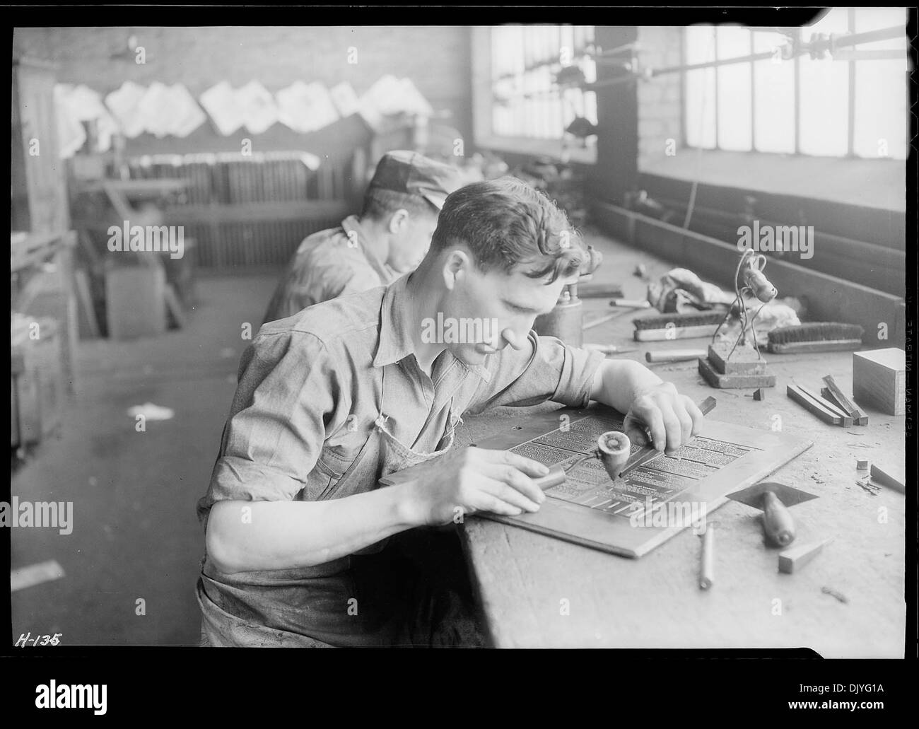 Hiram Hughes est photographié au travail dans le bâtiment Kingsport Press à Kingsport, Tennessee. L'image met en évidence l'environnement de travail industriel de l'époque, en se concentrant sur l'opération de presse. Banque D'Images
