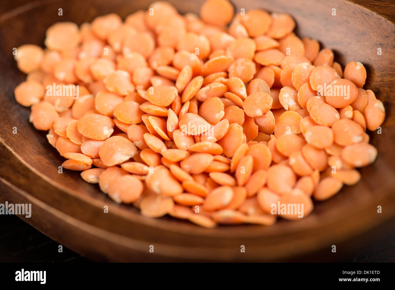 Les lentilles orange dans une cuillère en bois Banque D'Images