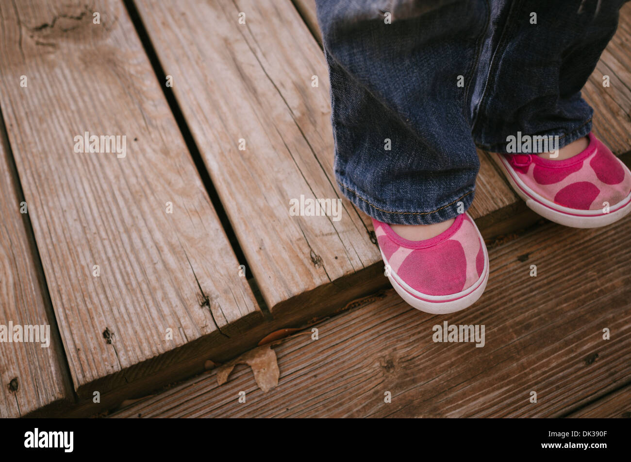 Chaussures de tennis rose de petite fille debout sur une terrasse en bois  Photo Stock - Alamy