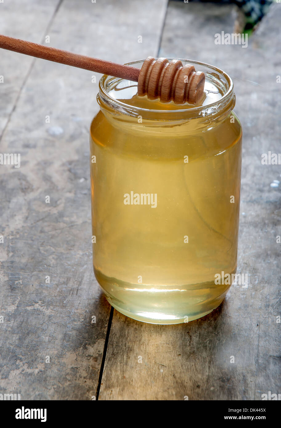 Pot de miel en verre avec balancier sur table en bois Banque D'Images