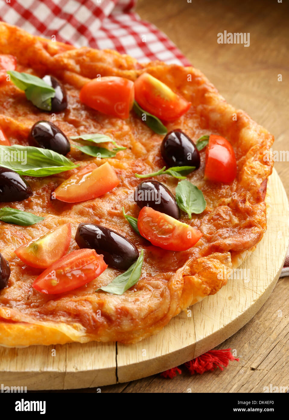Pizza italienne avec les olives et les tomates sur planche de bois Banque D'Images