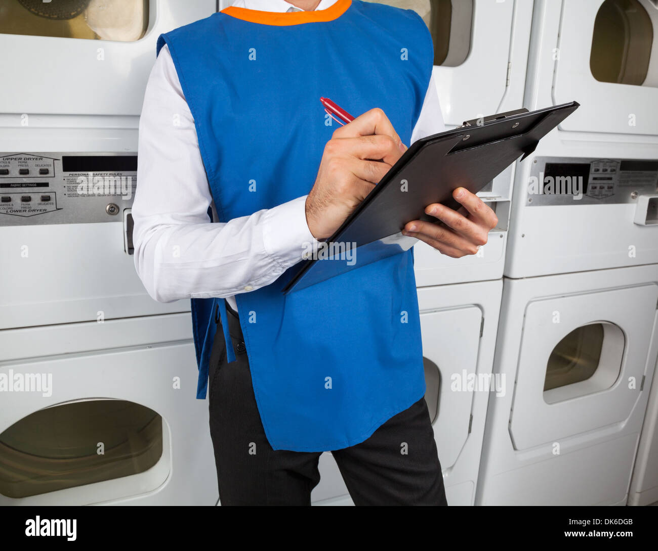 Helper mâle Writing On Clipboard In Laundromat Banque D'Images