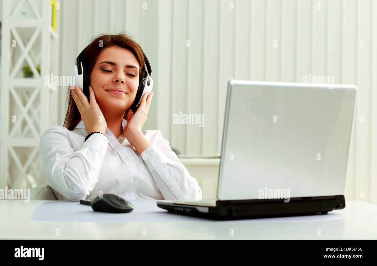Belle jeune businesswoman listening music in headphones at office Banque D'Images