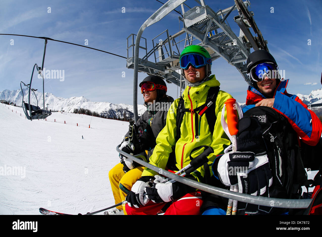 Grande photo de skieurs dans un télésiège sur une journée ensoleillée à la montagne, les pentes visibles dans l'arrière-plan Banque D'Images