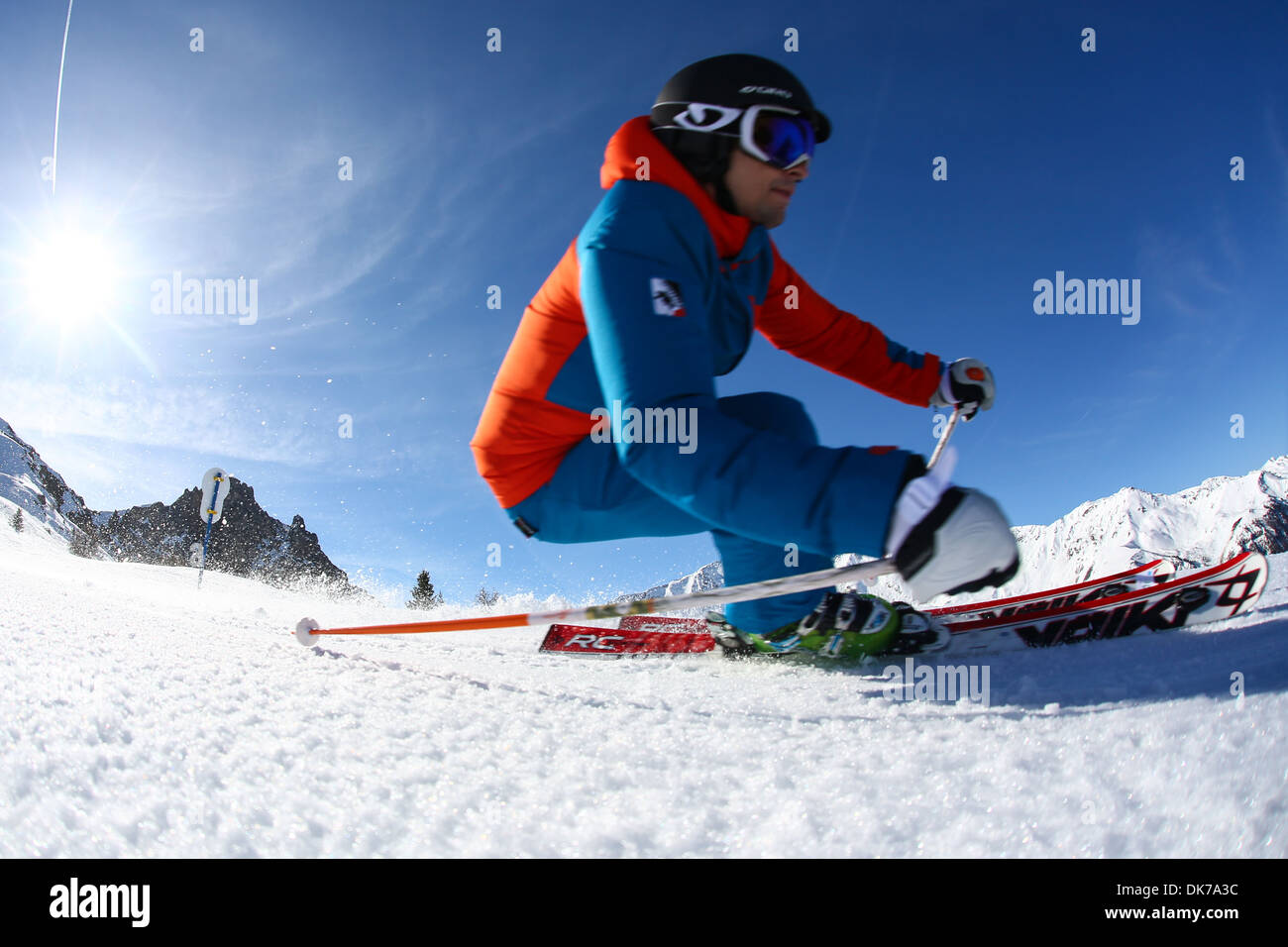 Large close up d'un skieur faisant un brusque tournant dans la neige sur une journée ensoleillée avec un ciel bleu Banque D'Images