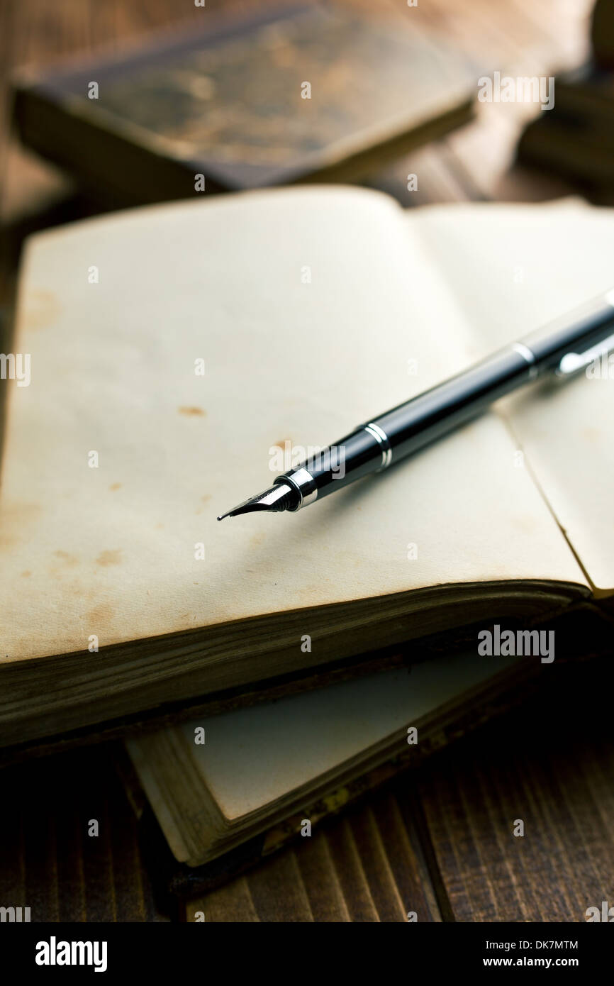 Ancien livre ouvert avec stylo plume sur table en bois Banque D'Images