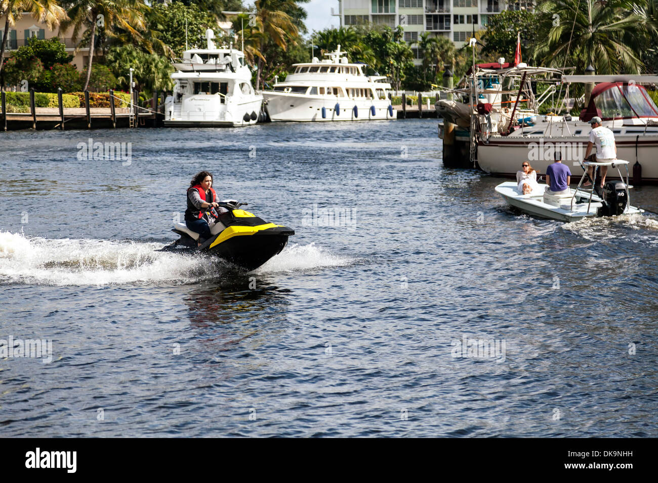 Young woman riding jet ski le long de la New River, au centre-ville de Fort Lauderdale, Floride, USA avec yachts amarré à l'arrière-plan. Banque D'Images