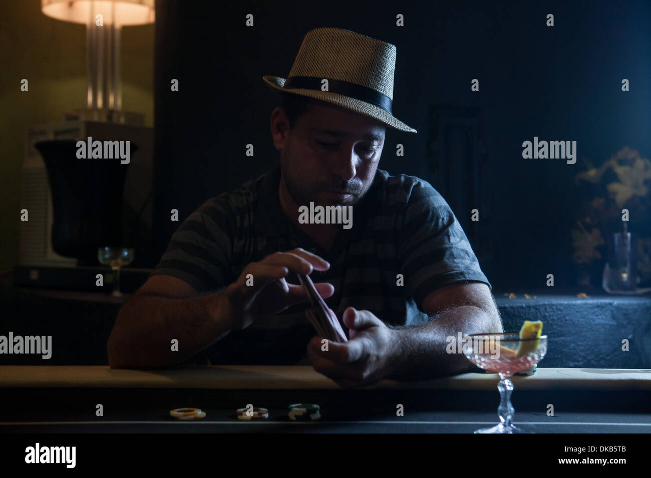 Mid adult man sitting at table shuffling cards Banque D'Images