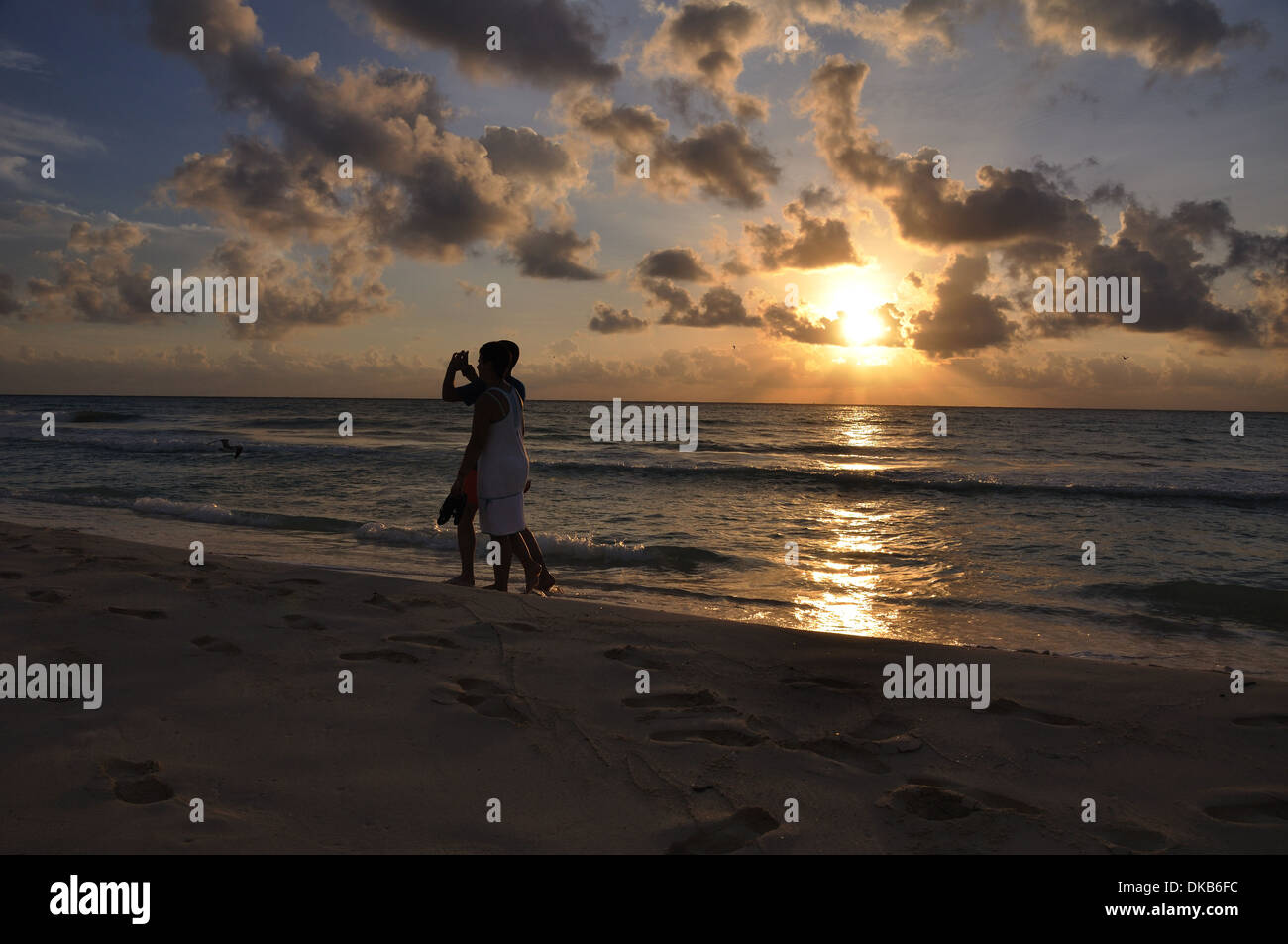 Deux jeunes hommes à prendre des photos sur une plage au lever du soleil, péninsule du Yucatan, Quintana Roo, Mexique Banque D'Images