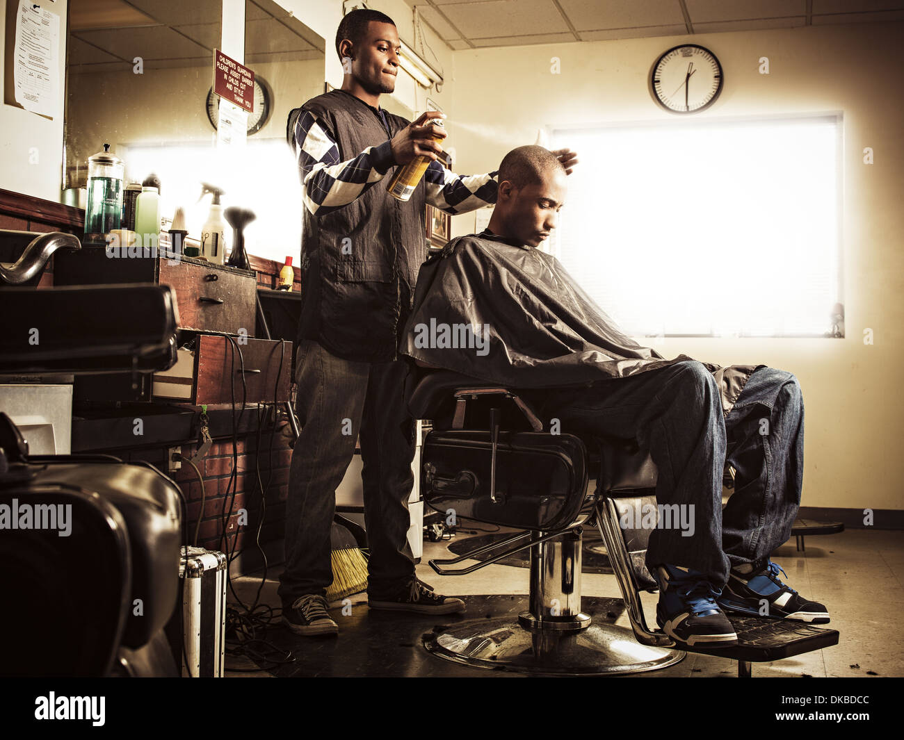 Salon de coiffure dans un salon de coiffure spraying hairspray sur l'homme Banque D'Images