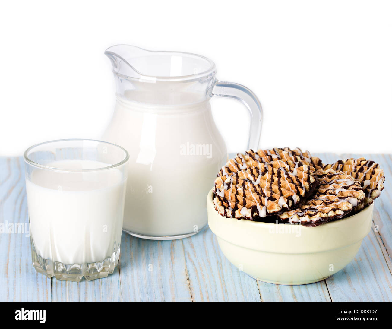 Composition du lait dans un pichet, un verre et des cookies sur blue background Banque D'Images