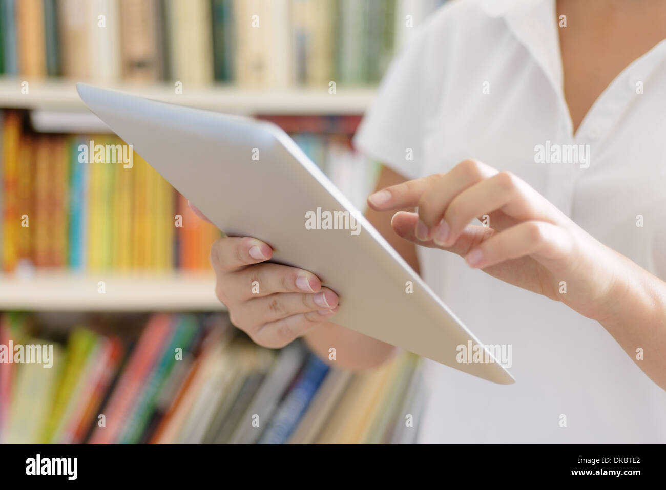 Les mains des femmes, holding tablet computer, des étagères à l'arrière-plan - ou la bibliothèque de classe du collège ou de l'intérieur de l'hôpital. Banque D'Images