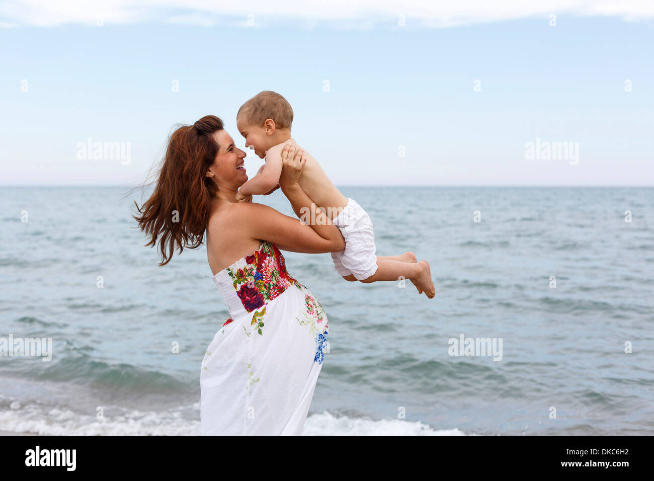 Femme Enceinte Enfant Sur La Plage De Levage Photo Stock - Alamy
