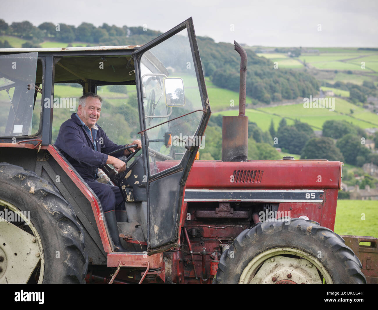 Farmer smiling mature dans le tracteur Banque D'Images