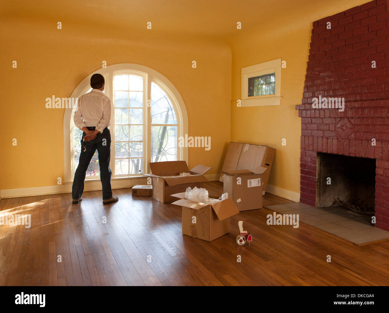 Un homme regarde par une salle vide dans une maison d'habitation et des boîtes en carton qu'il se déplace vers l'intérieur ou l'extérieur. Banque D'Images