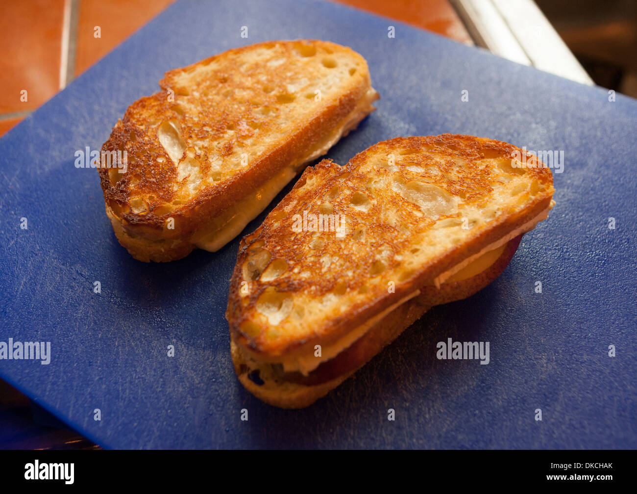 Sandwichs grillés au brie et aux poires sur une planche à découper en plastique. Banque D'Images
