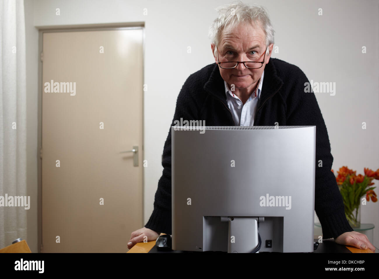 Senior man at home standing in front of personal comuter Banque D'Images