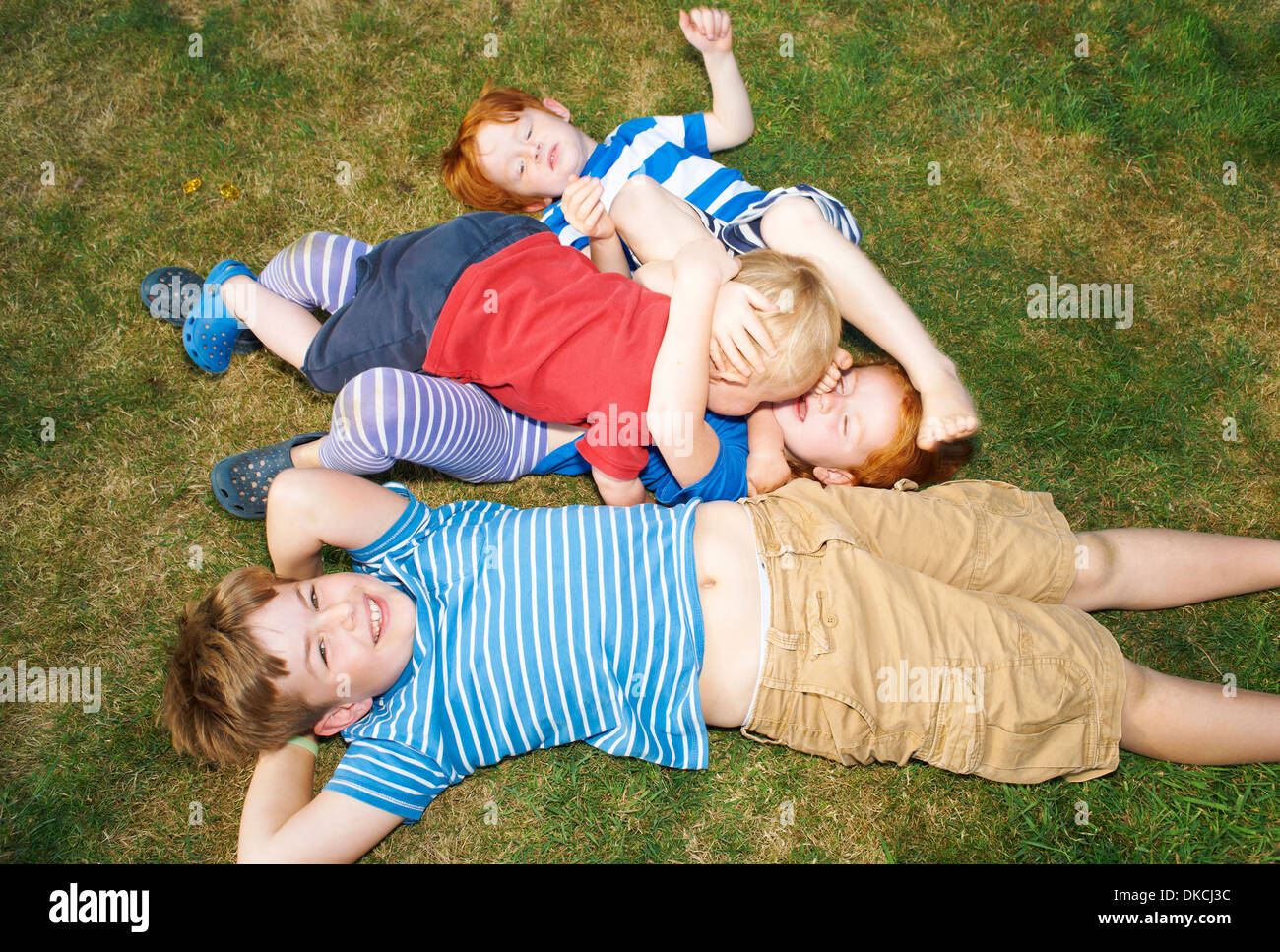 Trois frères et soeur lying on grass in garden Banque D'Images