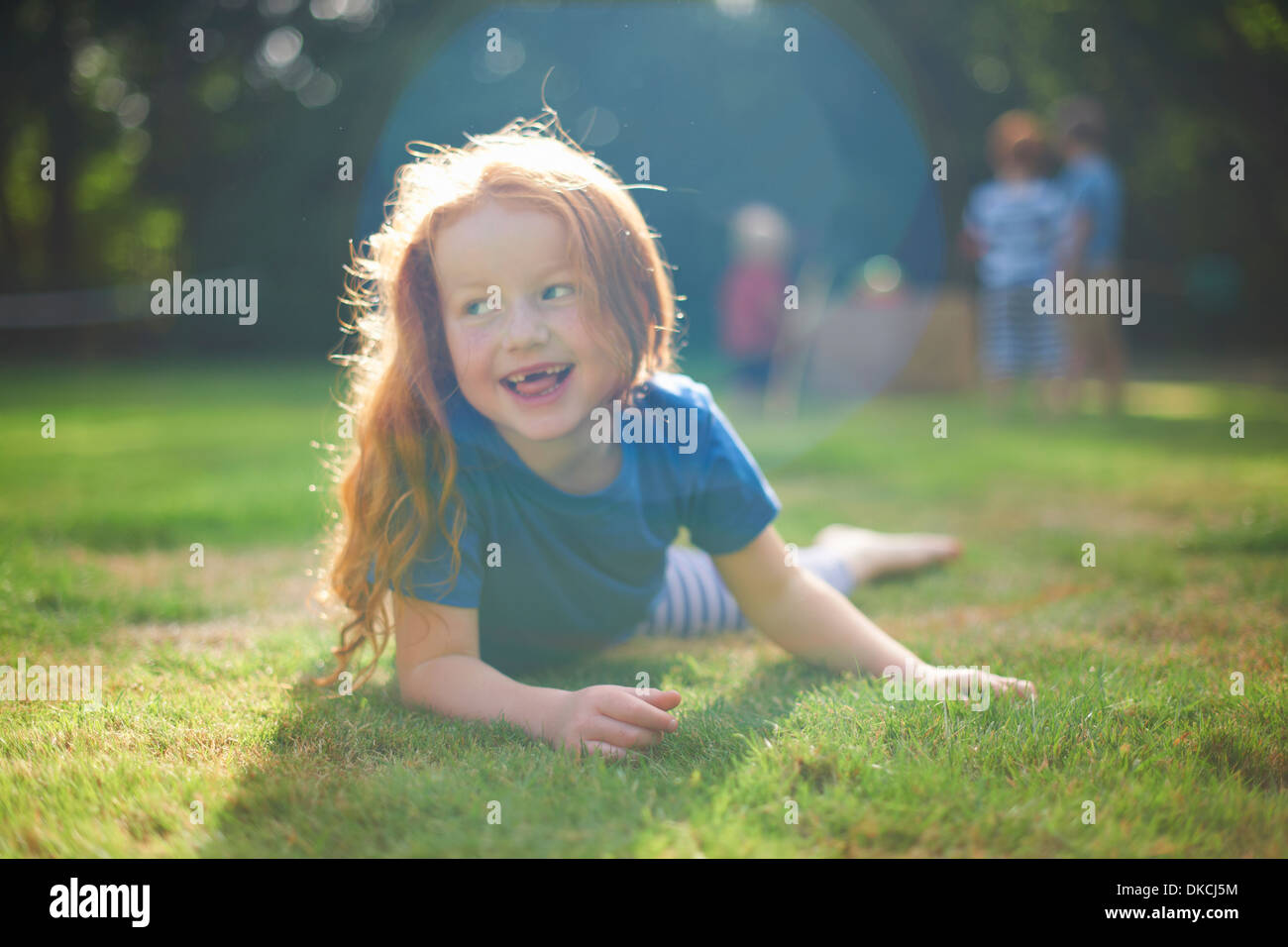 Happy young girl lying on grass in garden Banque D'Images